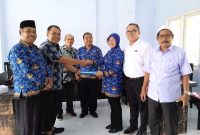 SIMBOLIS: Munawir Haris selaku pengarah dalam kepanitiaan di dampingi Plt Kadispora Lombok Barat Suparlan dan sekretaris KONI Lombok Barat Baharudin serta anggota panitia lainnya menyerahkan berkas kepada ketua panitia sebagai bentuk kesiapan panitia Musorkab KONI Lombok Barat tahun 2025. Foto )Doc.Istimewa).