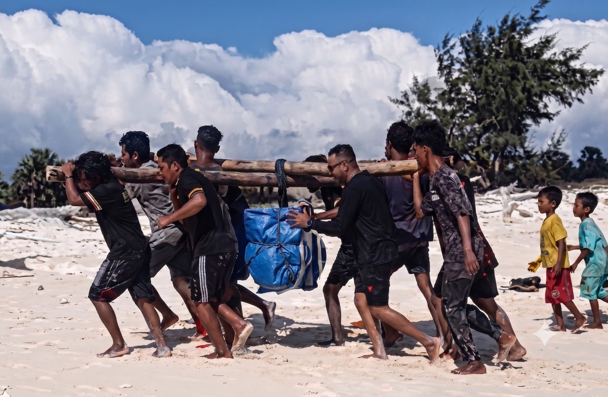 Petugas PLN Unit Layanan Pembangkit Listrik (ULPL) Waingapu bersama warga bergotong-royong mengangkut peralatan pemeliharaan pembangkit listrik setibanya di Pulau Salura, Sumba Timur, Nusa Tenggara Timur. Seluruh material dipindahkan secara manual dari bibir pantai menuju lokasi pembangkit karena keterbatasan akses transportasi. (PLN Dwipantara)