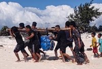 Petugas PLN Unit Layanan Pembangkit Listrik (ULPL) Waingapu bersama warga bergotong-royong mengangkut peralatan pemeliharaan pembangkit listrik setibanya di Pulau Salura, Sumba Timur, Nusa Tenggara Timur. Seluruh material dipindahkan secara manual dari bibir pantai menuju lokasi pembangkit karena keterbatasan akses transportasi. (PLN Dwipantara)