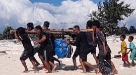 Petugas PLN Unit Layanan Pembangkit Listrik (ULPL) Waingapu bersama warga bergotong-royong mengangkut peralatan pemeliharaan pembangkit listrik setibanya di Pulau Salura, Sumba Timur, Nusa Tenggara Timur. Seluruh material dipindahkan secara manual dari bibir pantai menuju lokasi pembangkit karena keterbatasan akses transportasi. (PLN Dwipantara)
